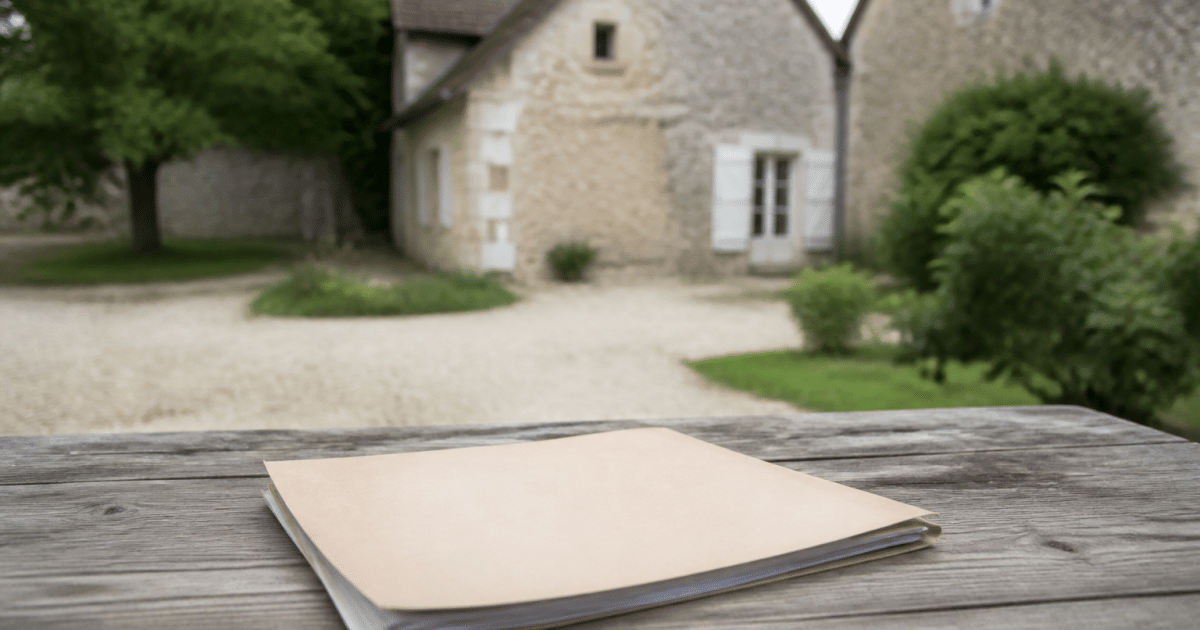 Document officiel pose sur table avec maison ancienne arriere-plan