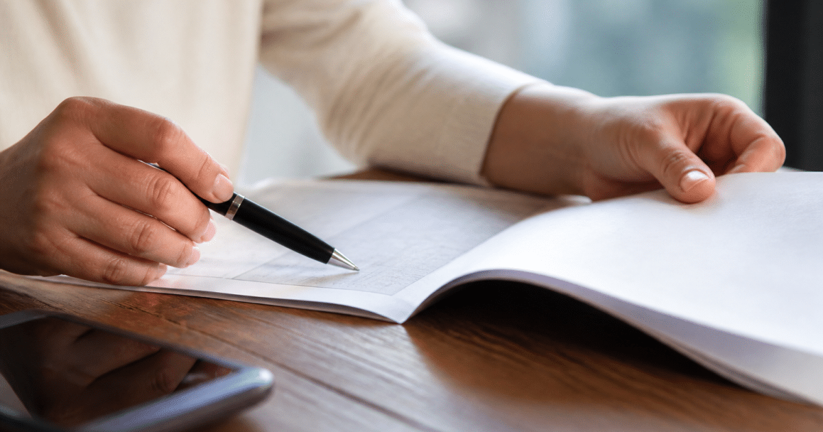 Document papier ouvert montrant texte contractuel avec stylo pointant clause specifique
