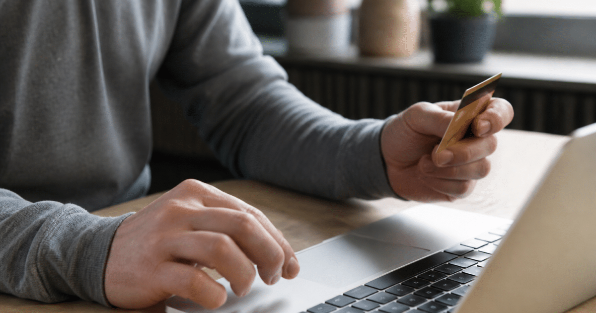 Personne saisissant carte bancaire au-dessus clavier ordinateur portable