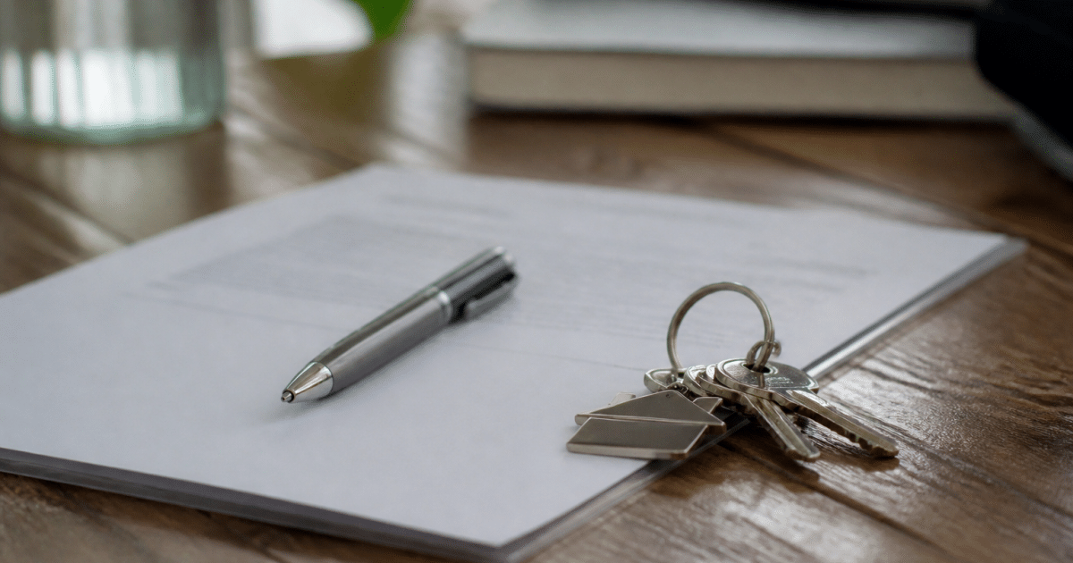 Document notarié posé sur table avec stylo et clés maison