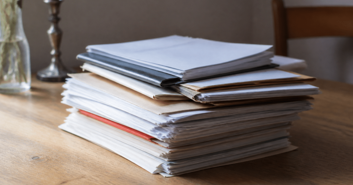 Documents immobiliers et testamentaires empiles sur bureau en bois clair