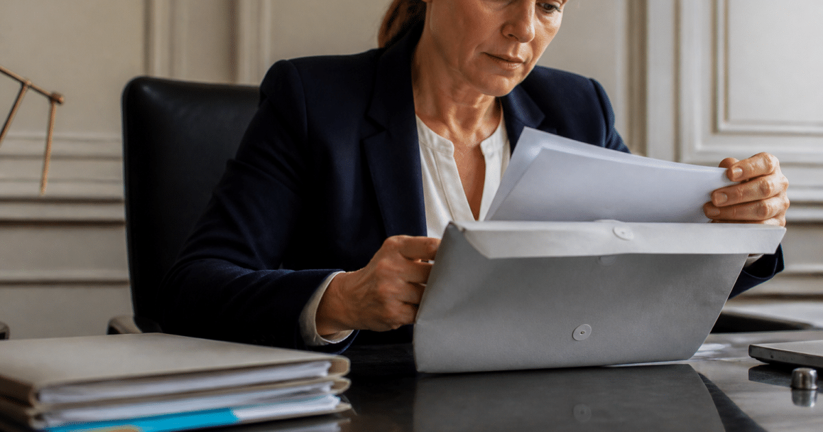 Notaire tenant documents immobiliers avec enveloppe argent sur bureau