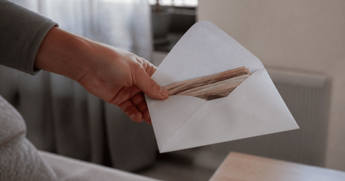 Main tenant une enveloppe blanche avec billets dedans