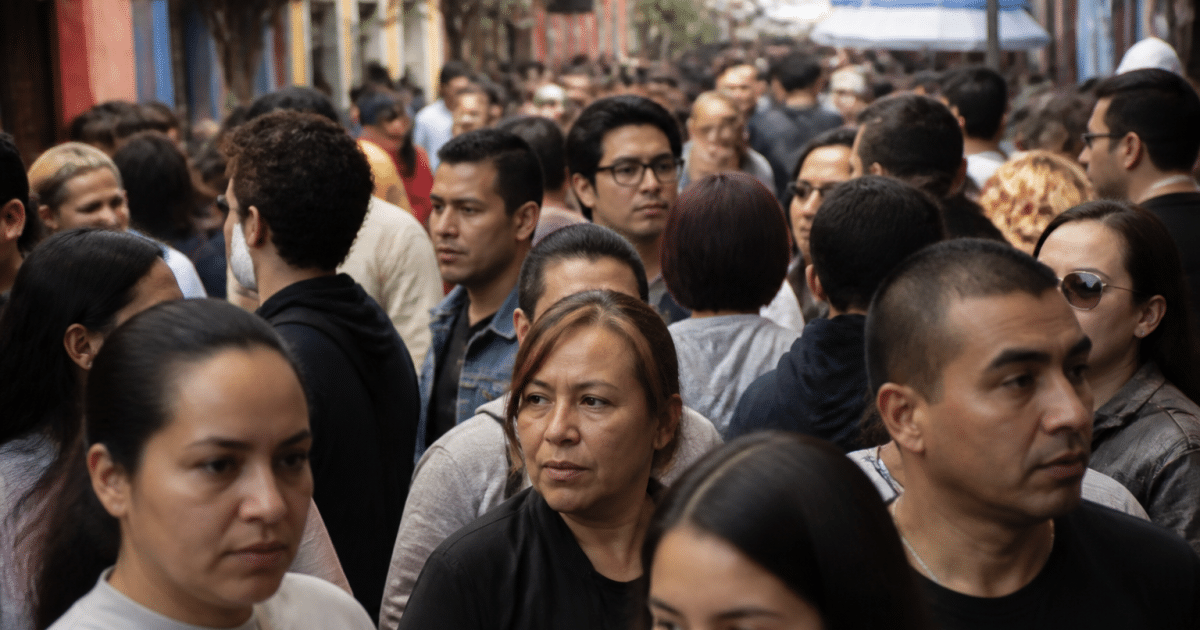 Foule dense de personnes debout serrées dans rue colorée