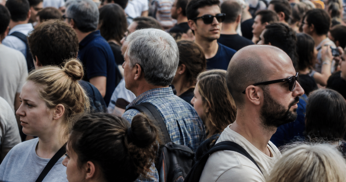 Foule dense de personnes debout cote a cote dans rue urbaine