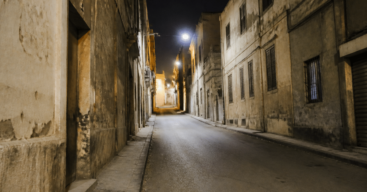 Rue urbaine avec immeubles degrades et rue vide la nuit