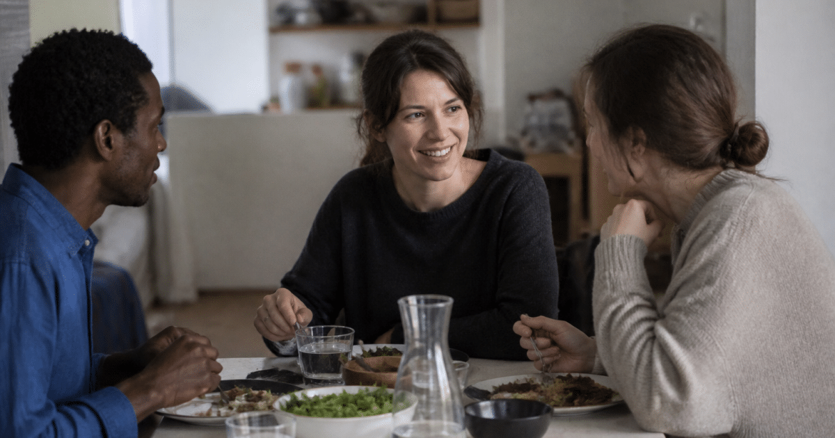 Trois personnes assises autour table repas ensemble